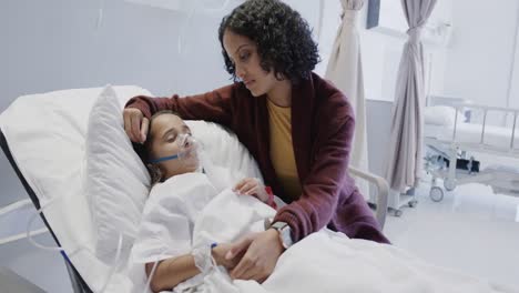 worried biracial mother and her sick daughter patient with oxygen mask in hospital in slow motion