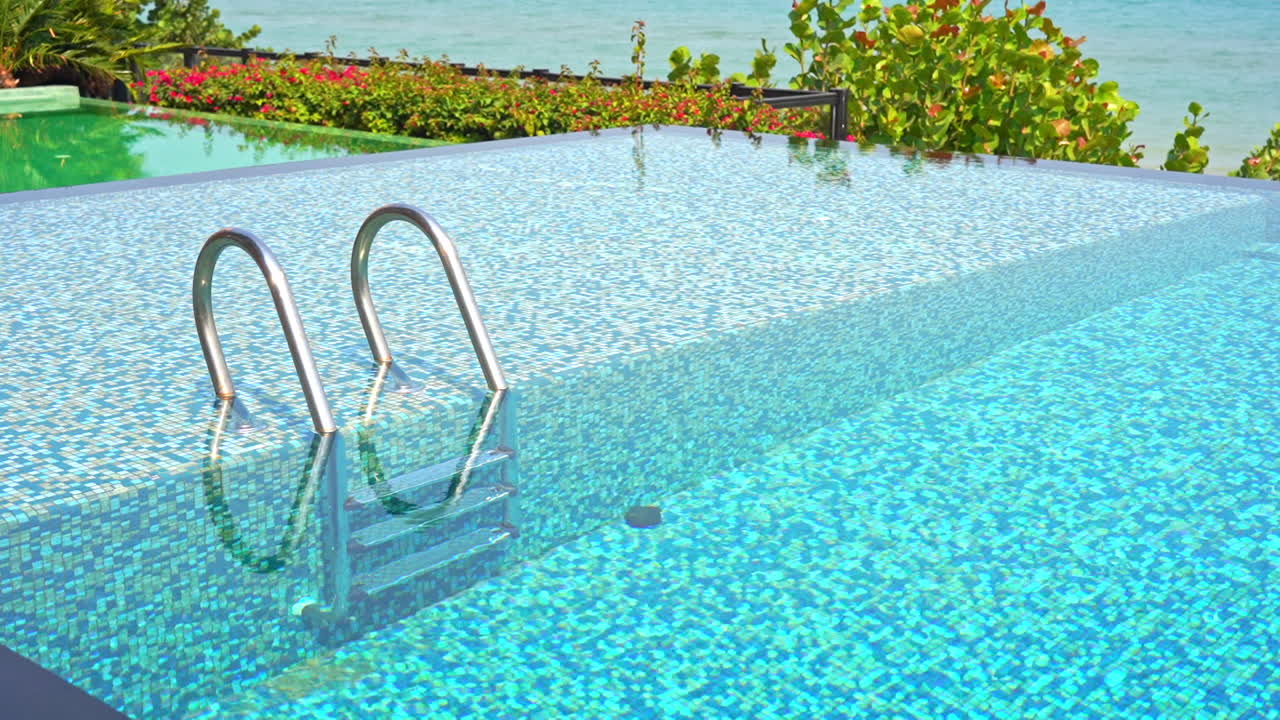 Luksuriøst poolområde, blåt vand og pooltrapper.