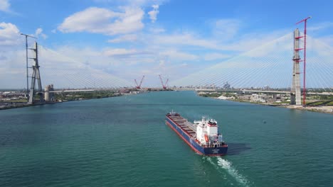 cargo vessel on detroit river approaching gordie howe international bridge in a building process