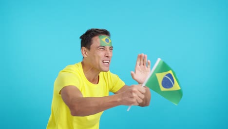 brazilian supporter screaming and waving a national flag looking away