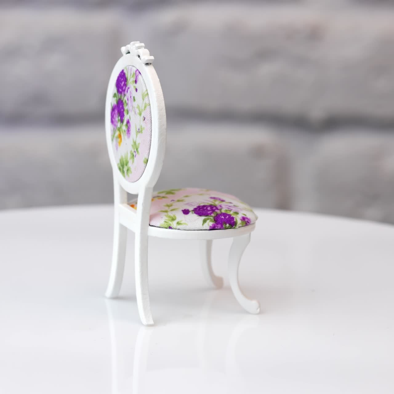 Cute miniature wooden curved chair with flower print. Toy piece of furniture rotating at white backdrop
