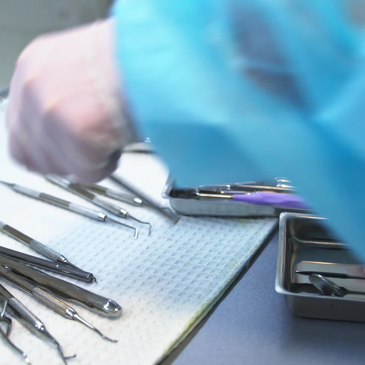 Hands of medic nurse arranges metal tools. Medical worker placing instruments into little metal boxes. Close up