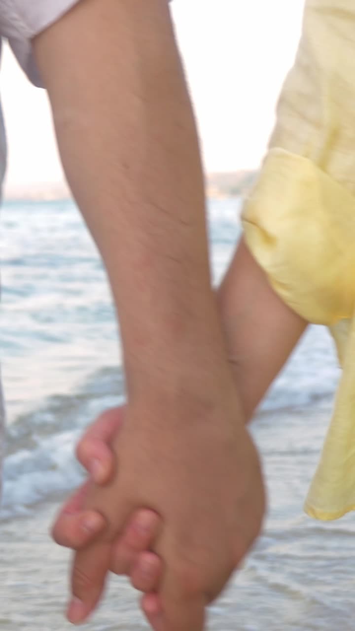 Una pareja de manos en la playa.