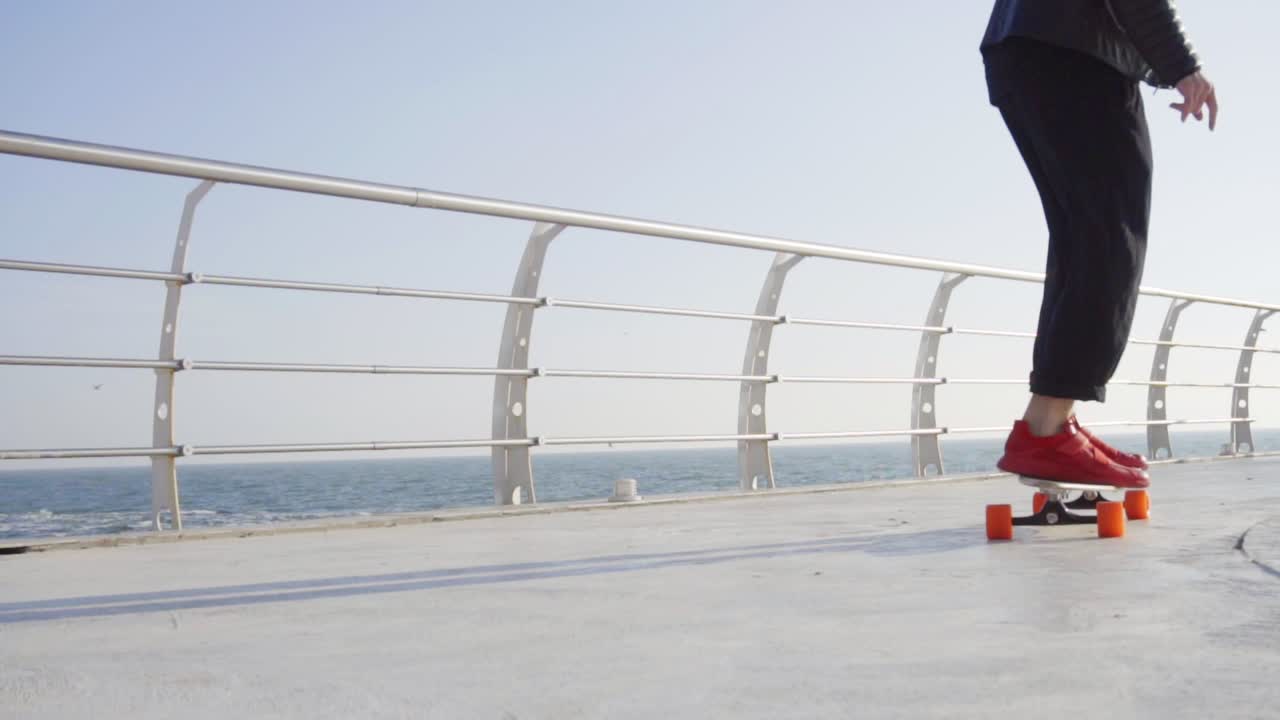 빨간 운동화를 입은 남자가 바다  ⁇ 에서 롱보드에 스케이트를  ⁇ 고 있다.
