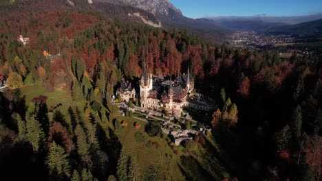 Castillo-De-Peles-Con-árboles-De-Colores-Otoñales-Al-Atardecer,-Mostrando-Arquitectura-Histórica,-Vista-Aérea