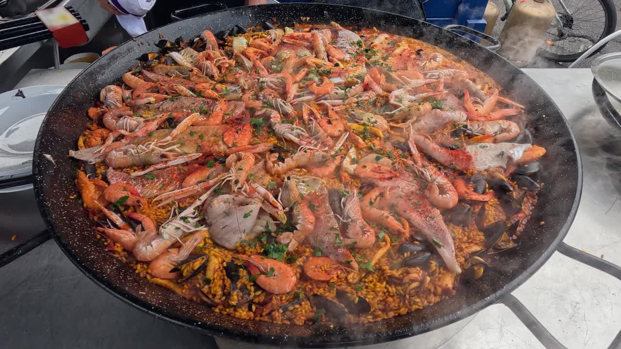 Enormous discada wok cooks paella on street with rice and seafood