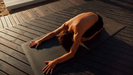 The-guy-took-a-special-pose-for-yoga-and-stretching-on-a-special-mat-on-a-sunny-beach-in-the-morning