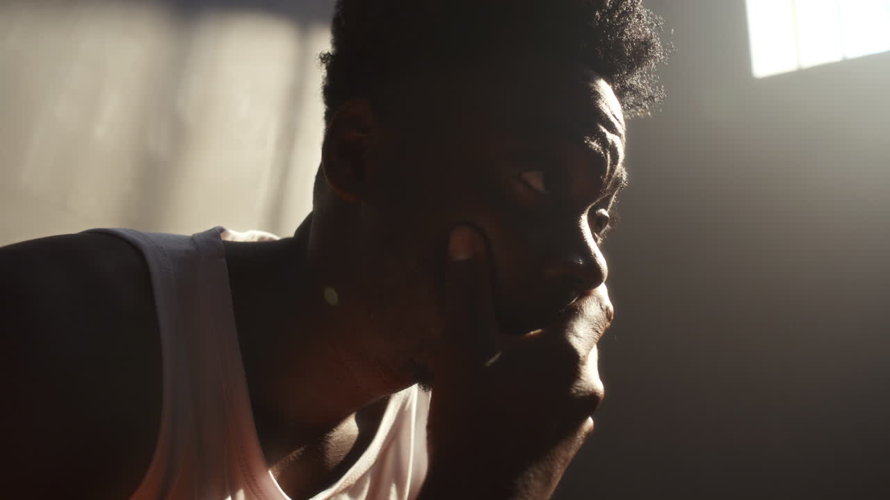 Distressed African American Inmate Sitting in Sunlit Prison Cell