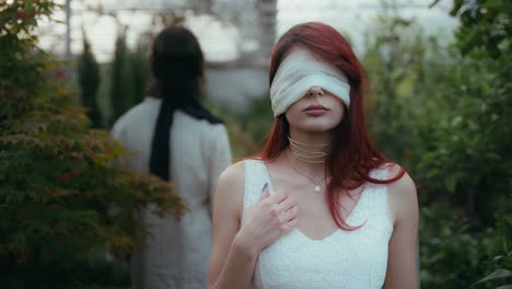 Cinematic-slow-motion-video-of-blindfolded-young-couple-turning-to-look-each-other-in-greenhouse-illuminated-by-natural-daylight