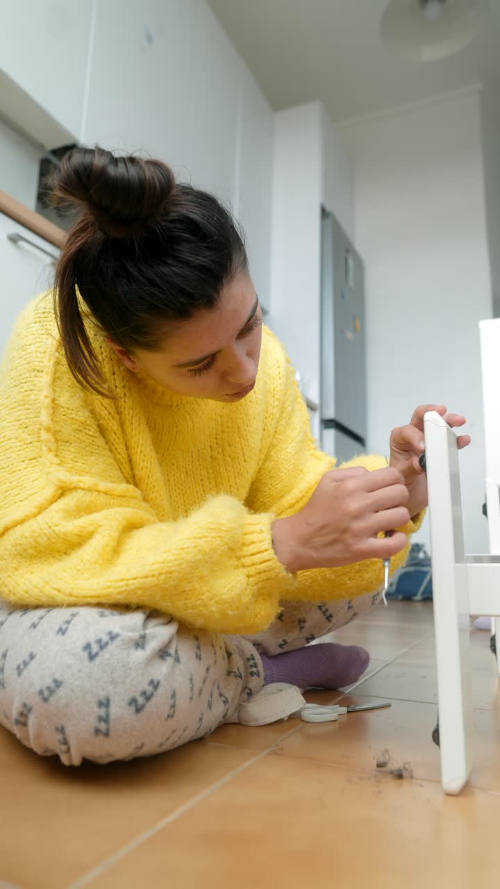 Giovane donna che assembla mobili sul pavimento a casa