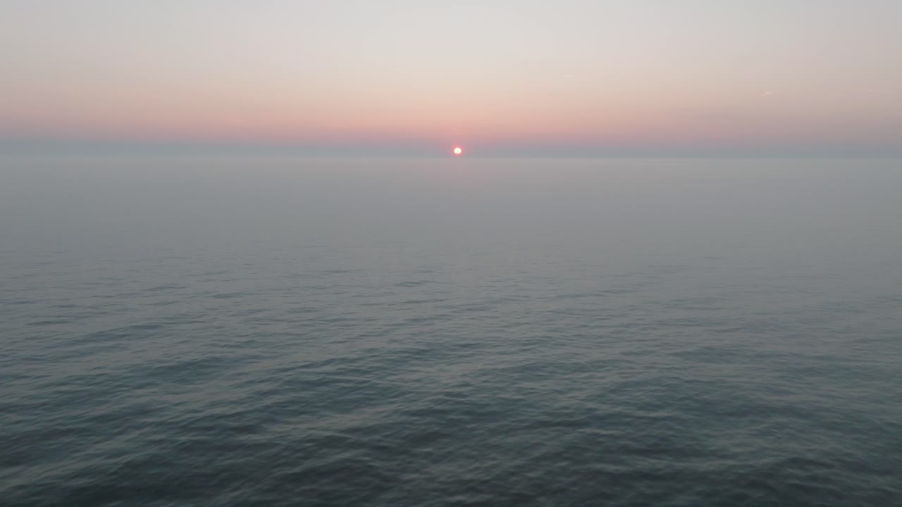 평온한 발트해 위의 활기찬 높은 대조적인 일몰의 아름다운 공중 전망, 지평선에 구름, 카로스타 전쟁 항구 콘크리트 해안 요새 폐허 리파자, 상승 드론  ⁇  앞으로 이동