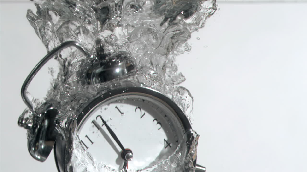 Premium stock video - Alarm clock in super slow motion falling in the water