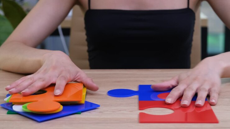Mujer ensambla grandes piezas de rompecabezas alineando bordes coloridos.