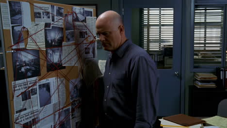 a detective analyzing an evidence board with red string