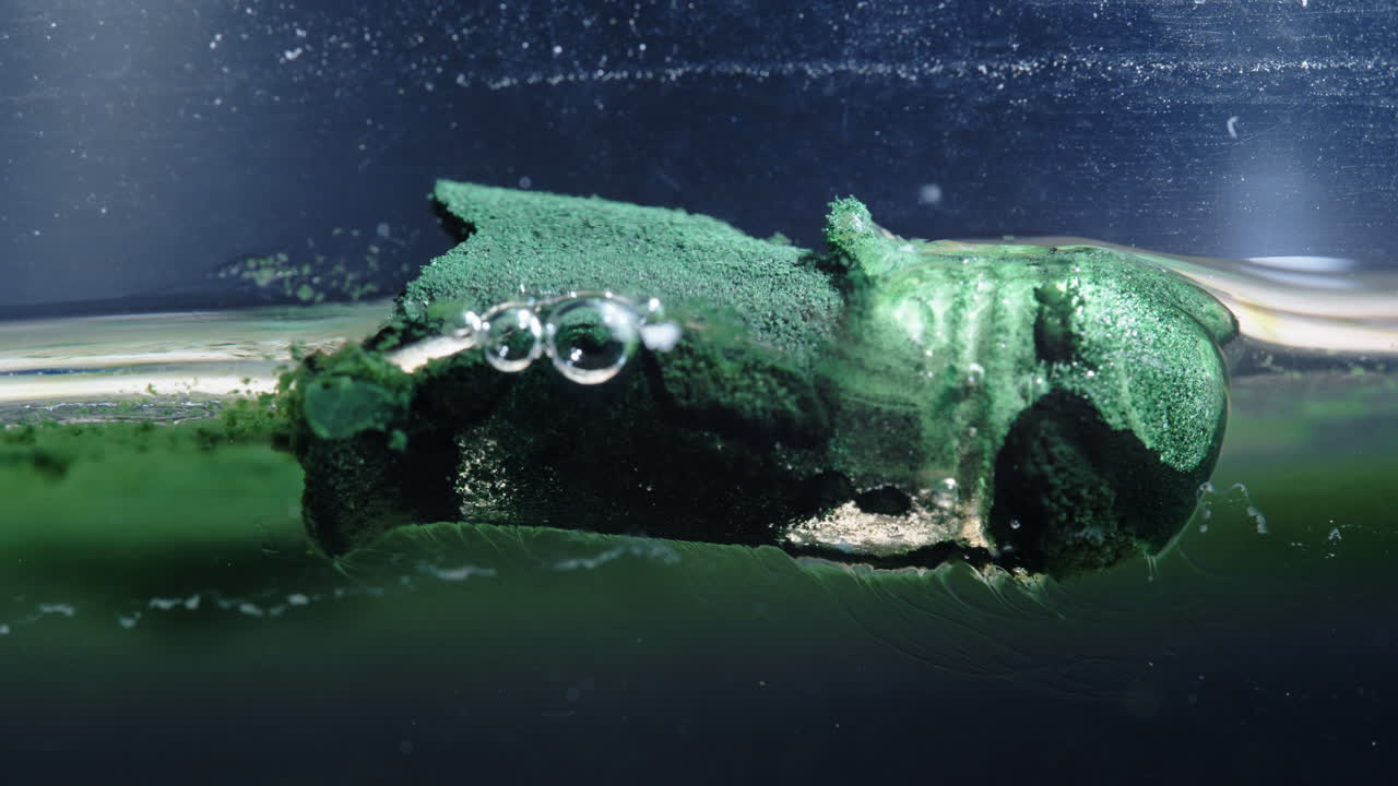 Dissolving pill underwater with bubbles forming and dissolving in water