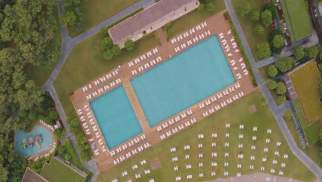 aerial view of a resort swimming pool with surrounding landscape and deck chairs