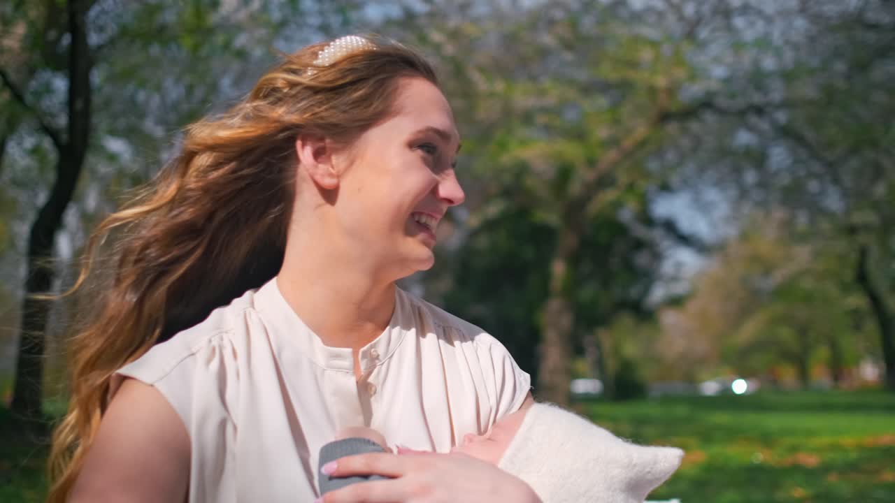 엄마 가 공원 에서 피크닉 을 하는 동안 새로 태어난 아기 를 들고 웃고 있다