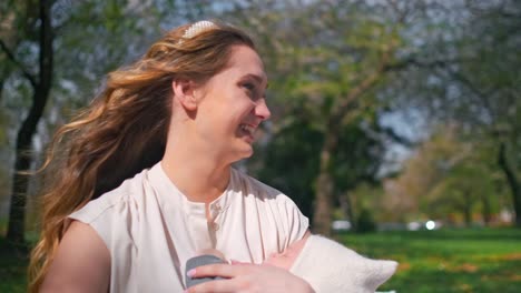 Mom-laughing-and-holding-a-newborn-baby-during-a-picnic-at-a-park