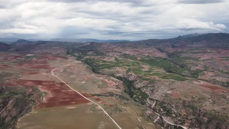 una toma del cielo de un valle verde al lado de una carretera en las tierras altas de cuzco