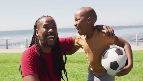 video of happy african american father and son having fun with ball outdoors