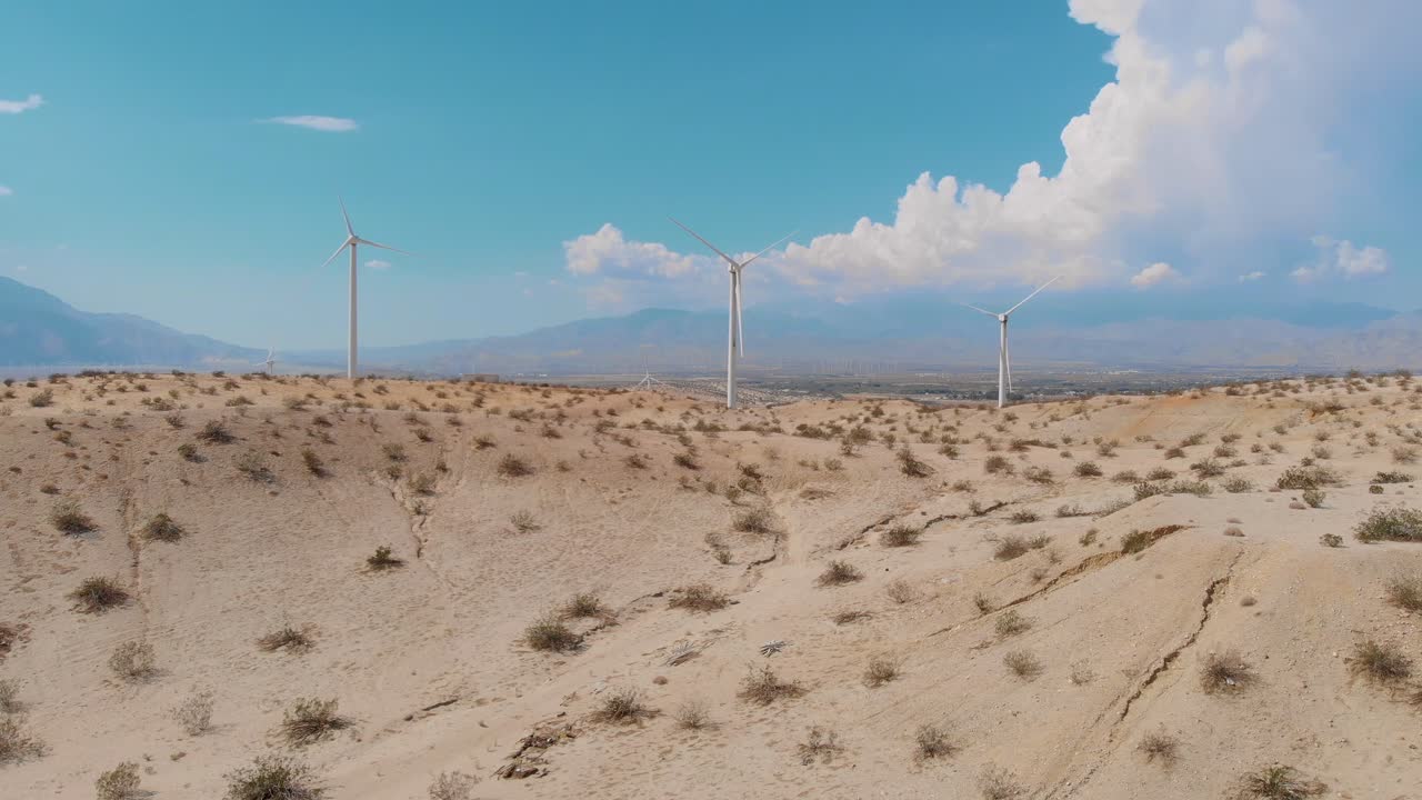 lento volar arriba y por encima de las colinas cubiertas de arena y molinos de viento cerca de la pequeña ciudad desértica