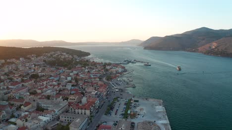 Flyover-Argostoli-coastline-downtown,-beautiful-sunset-colors-in-Horizon,-Kefalonia-Island