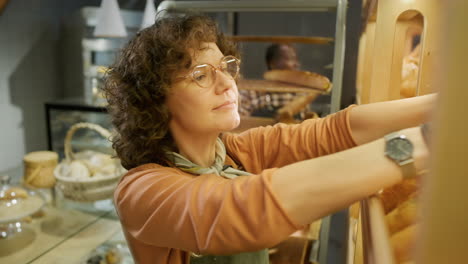woman baker handling baguettes in bakery