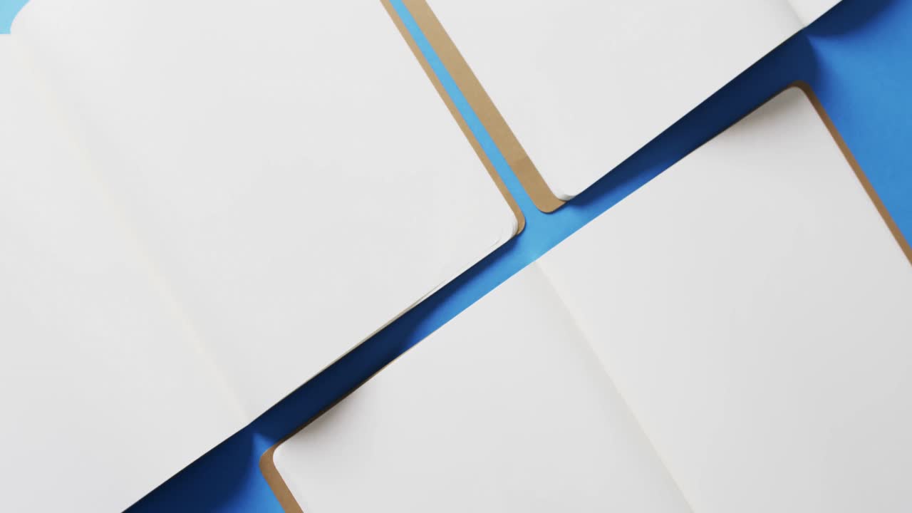 close up de libros en blanco abiertos con espacio de copia en fondo azul en cámara lenta