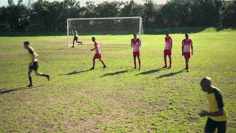 playing soccer, player in yellow jersey taking free kick towards goal