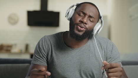 hombre negro cantando con auriculares. retrato de hombre feliz bailando con el cuerpo