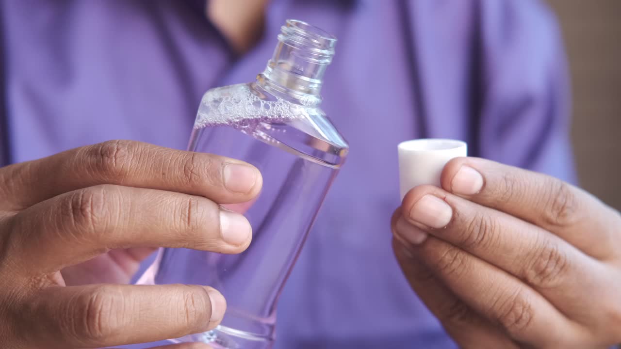 persona vertiendo enjuague bucal en una taza