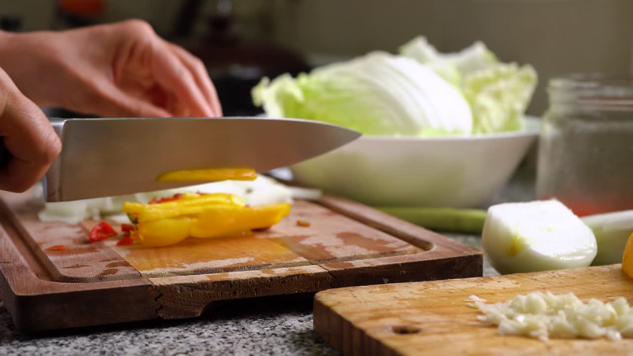 manos cortando pimiento amarillo en tiras en la cocina