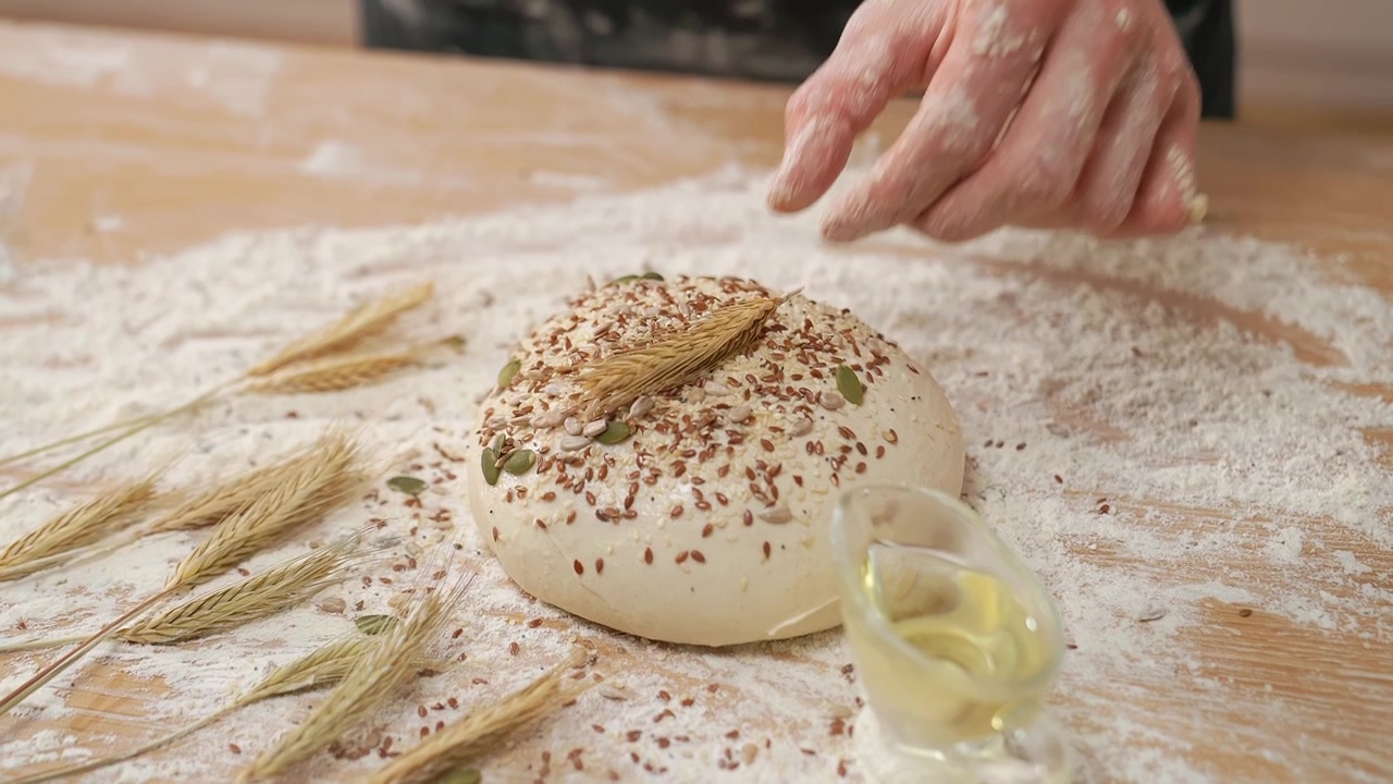 Hand Decorating Raw Bread Dough with Wheat Ear and Seeds