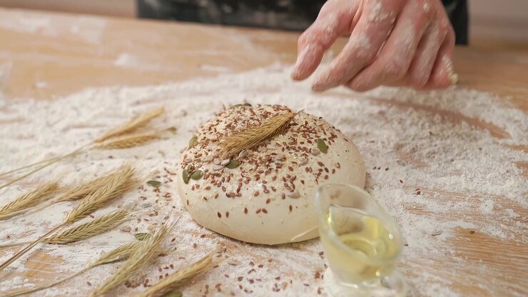 Hand Decorating Raw Bread Dough with Wheat Ear and Seeds