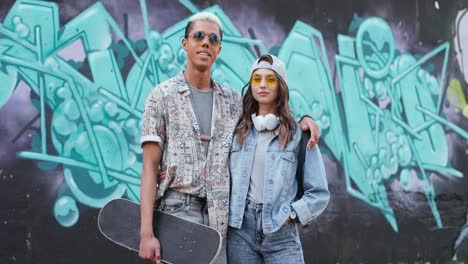 포옹과 카메라에 미소 사랑에 세련 된 옷에 hipster 커플