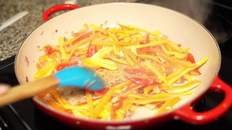 stirring of veg cuisine having carrots, capsicums in frying pan.