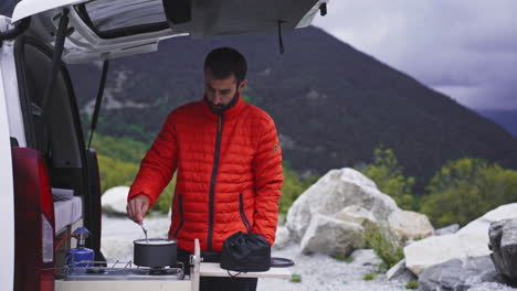 male trekker camper climber cooking food outdoor in his own camping car van life