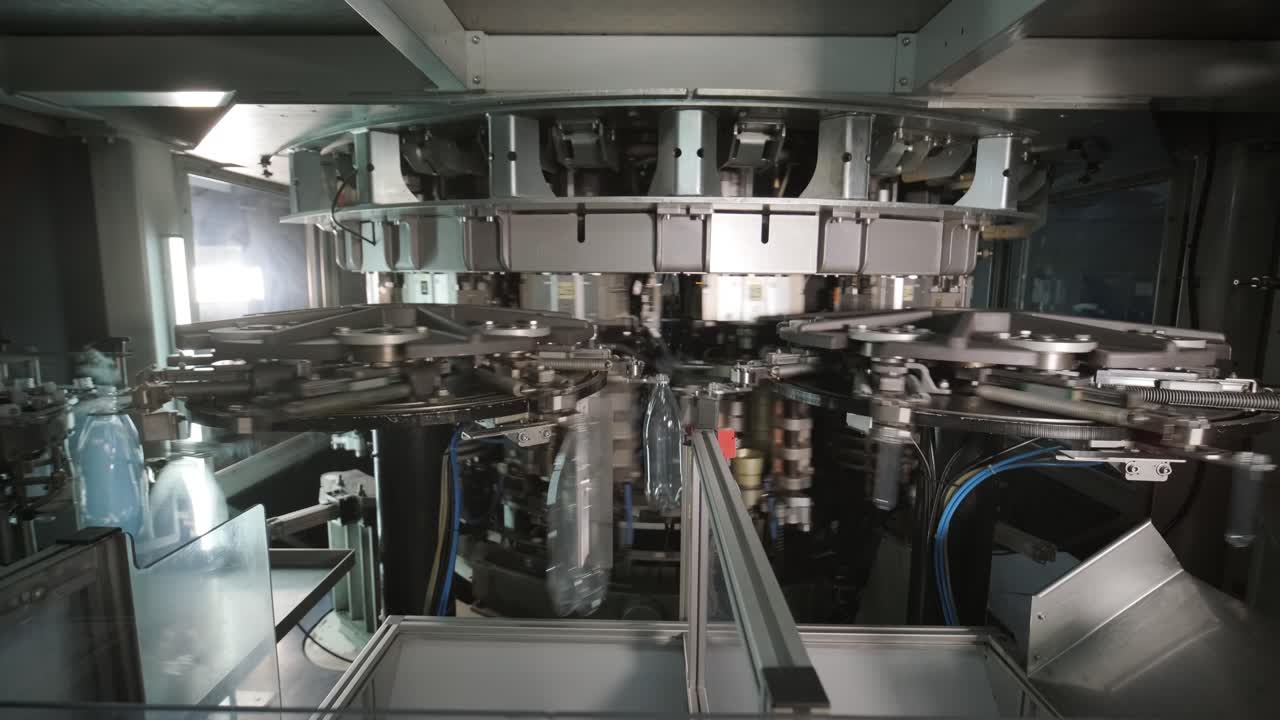 Automatic filling machine pours water into plastic PET bottles at modern beverage plant