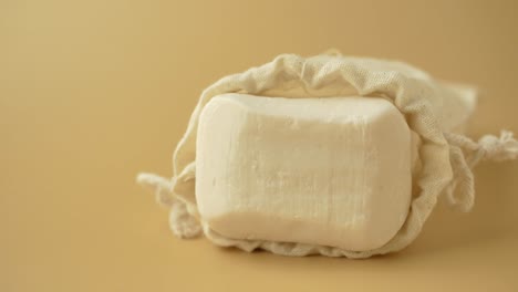 una barra blanca de jabón en una bolsa de algodón
