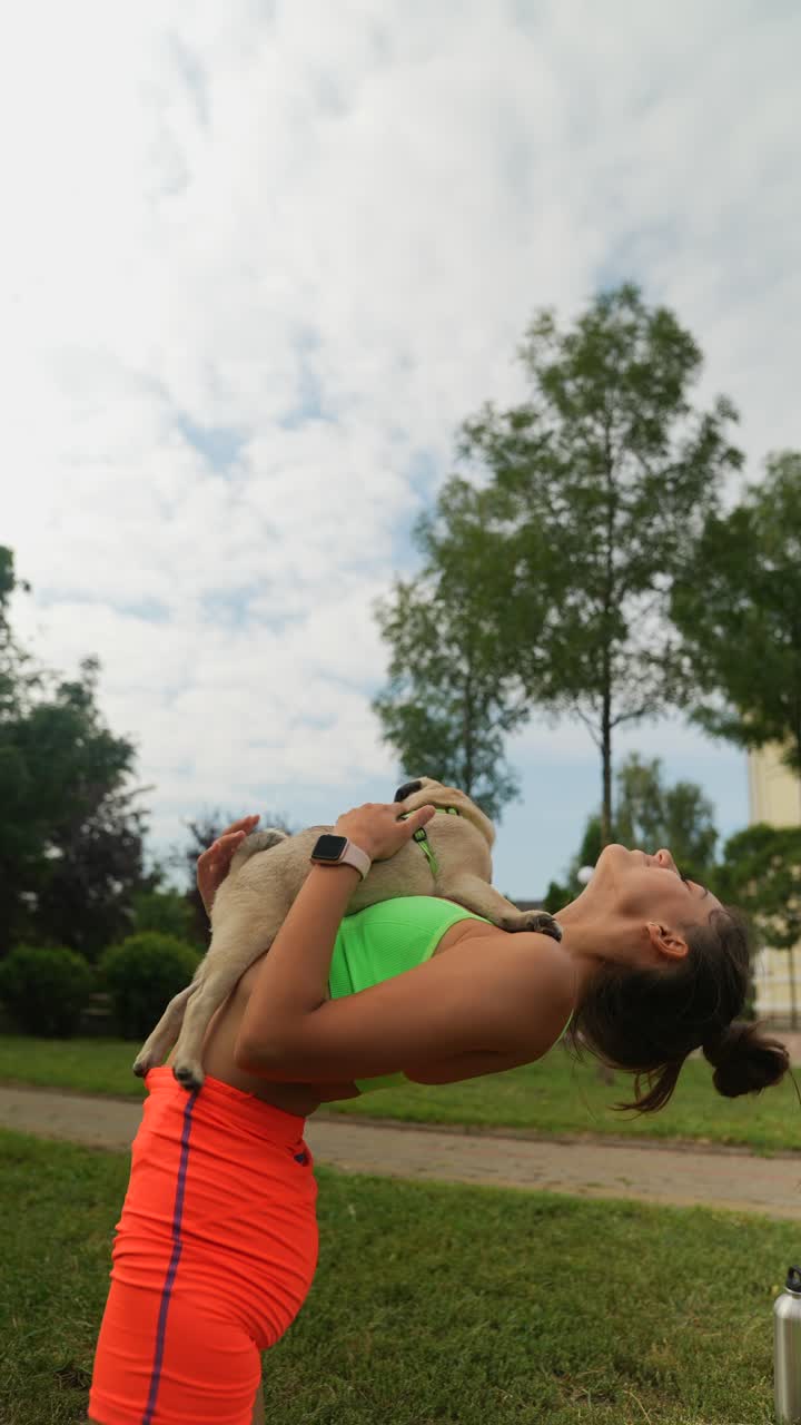 mujer practicando yoga con un cachorro en un parque