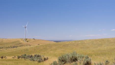 turbina eólica en un campo de idaho, amplia con tierras de cultivo y colinas de artemisa en un caluroso día de verano en el este de idaho en 4k