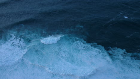 ocean scene with large, turbulent waves in madeira dark blue water contrasts with the white foam power of the waves crashing and swirling near the surface