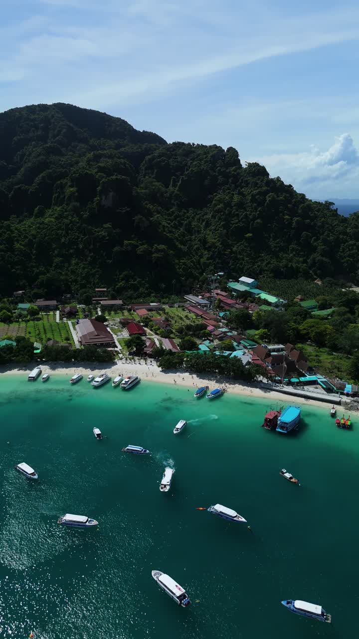 Drone pans vertically over Loh Dalum Beach, boats and reefs on Phi Phi Don in the Andaman Sea