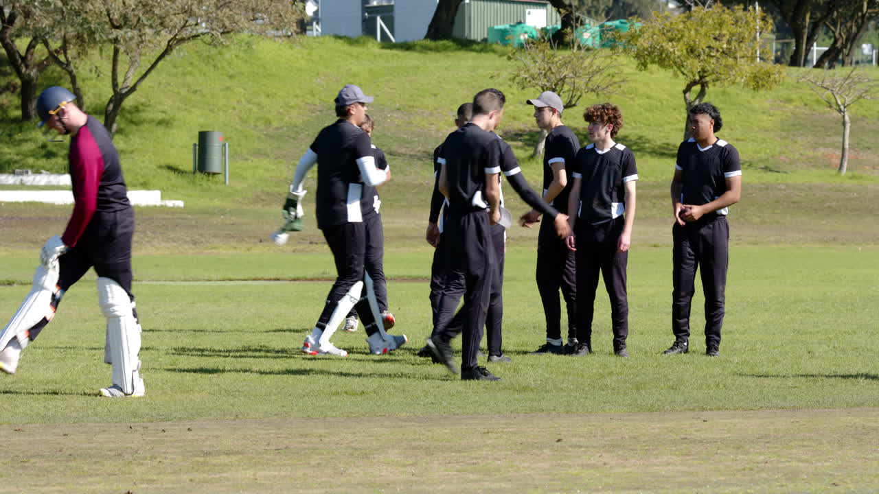 Two teams of multiracial male cricket players playing cricket on pitch