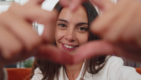 happy girl makes symbol of love, showing heart sign to camera, express romantic feelings, charity