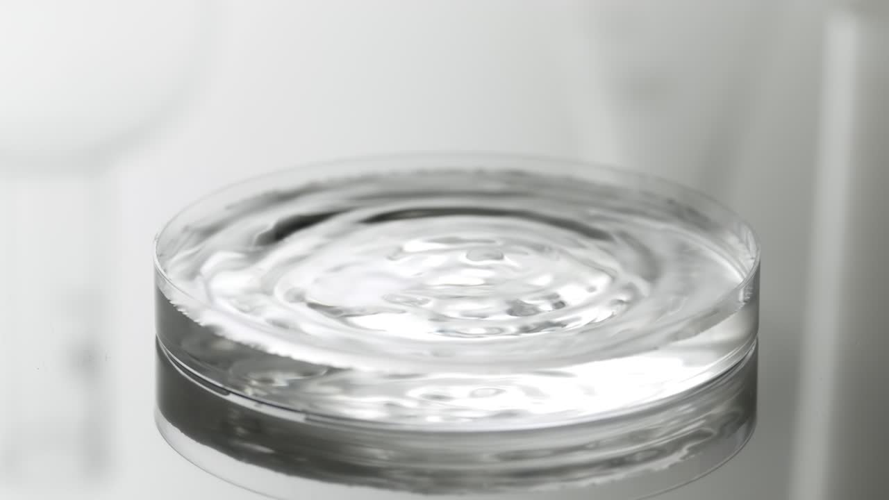 물방울은 파동을 일으키는 액체와 함께 페트리 접시에 떨어집니다.