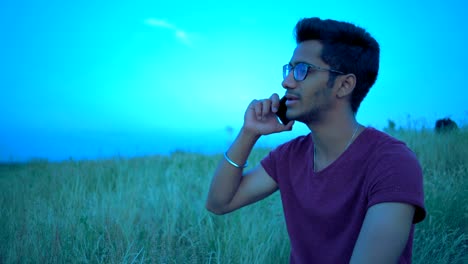 Close-up Plan, Indian Man Conducting a Conversation on a Phone on the Background of the Evening Sky