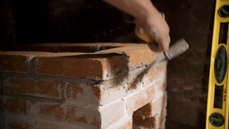 low closeup of mexican man putting together small brick stove