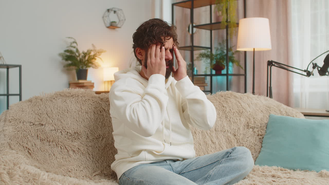 Displeased young man rubbing temple to cure headache problem suffering from tension and migraine