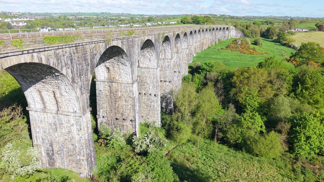 Historisk jernbaneviadukt i stein strekker seg over en frodig grønn dal på landsbygda i Nord-Irland